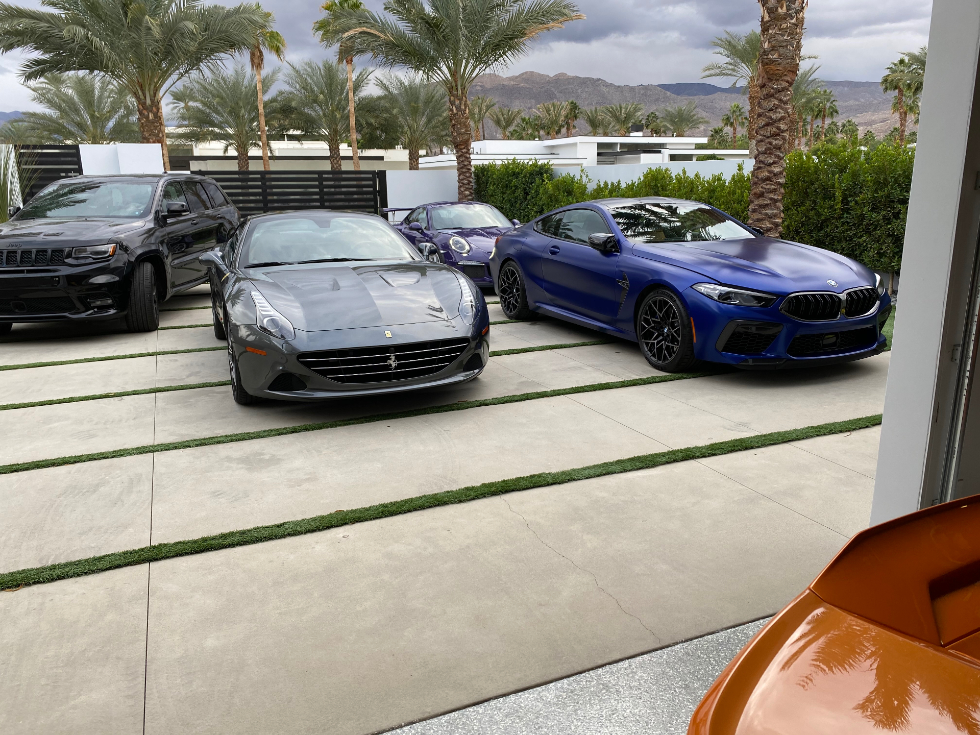 Joe Colangelo's driveway lineup: a grey Ferrari California, a purple Porsche 911 GT3 RS, a blue BMW M8 and an orange Lamborghini Huracan