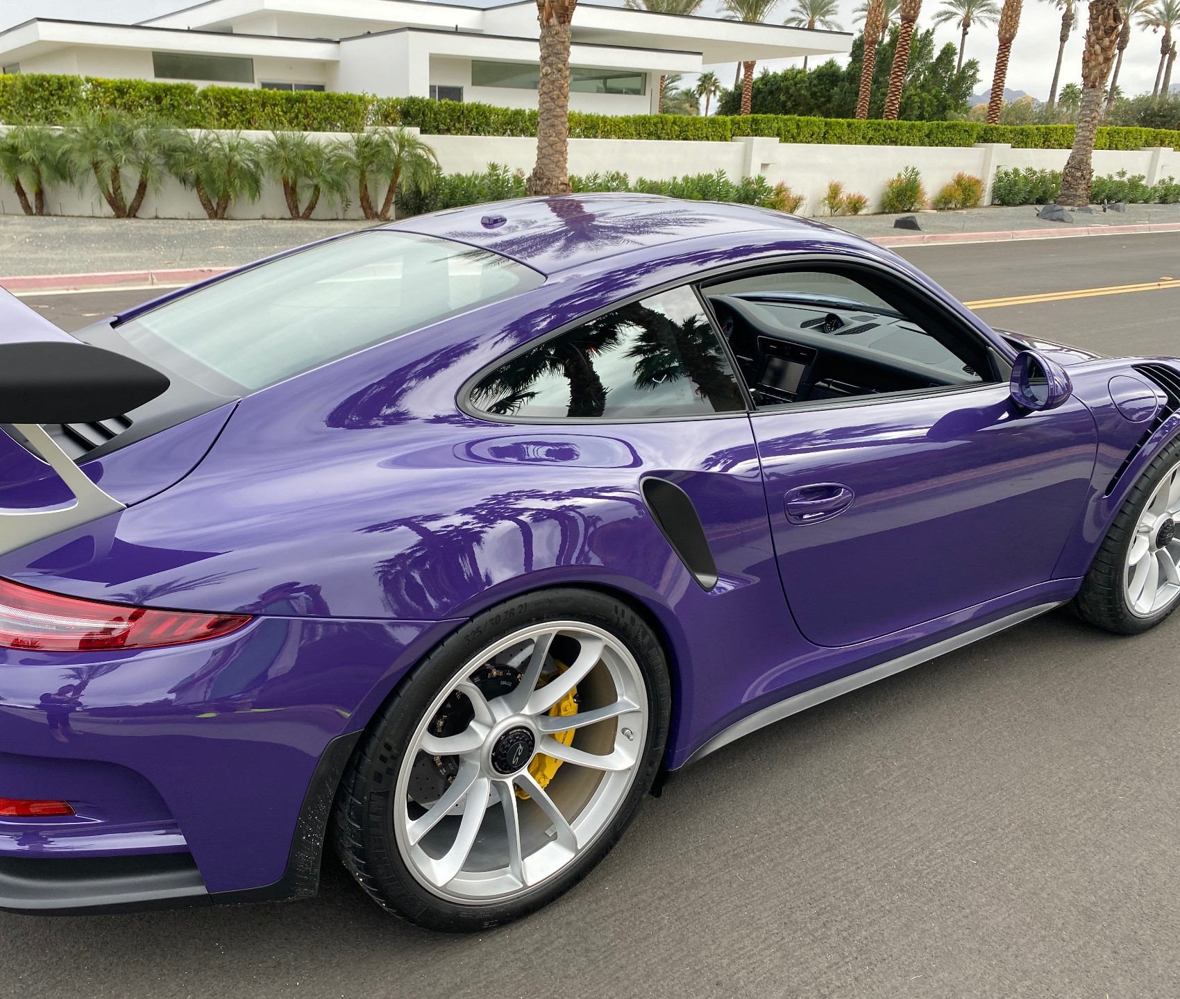A violet Porsche 911 GT3 RS with its rear wing raised, freshly washed